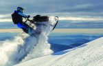 A,Snowmobile,Rider,Jumps,In,A,Mountain,Valley,At,Dawn.